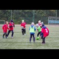 Dzieci grają w piłkę nożną na boisku. 